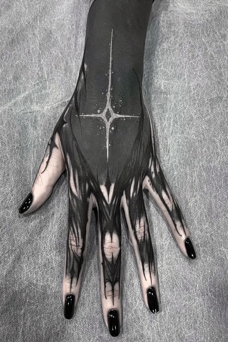 hand with a blackout tattoo and a black manicure